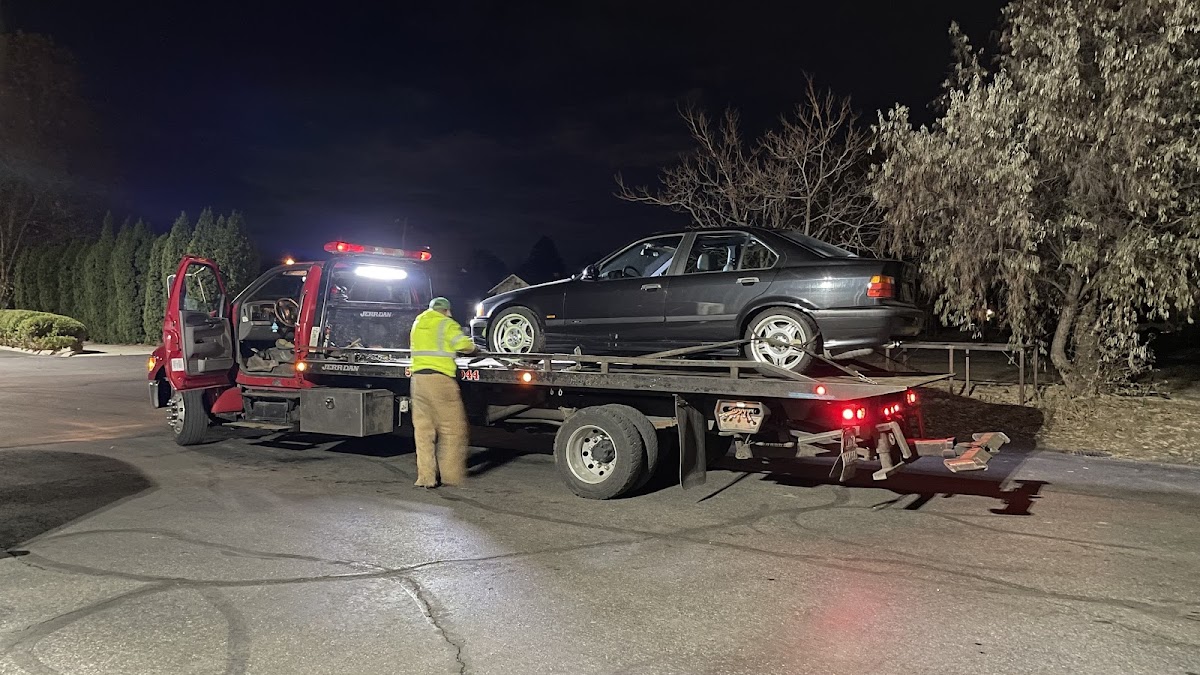 A Bradley's Towing flatbed loading a car at night in the Tri-Cities